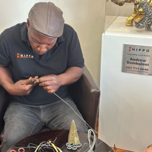 Craftsman working on delicate wire artwork in a hotel lobby, showcasing local art and handmade decor pieces