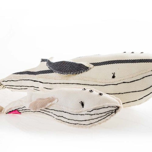 Two fabric whale toys in black, white, and beige with stitched details, showcasing playful and eco-friendly decor options