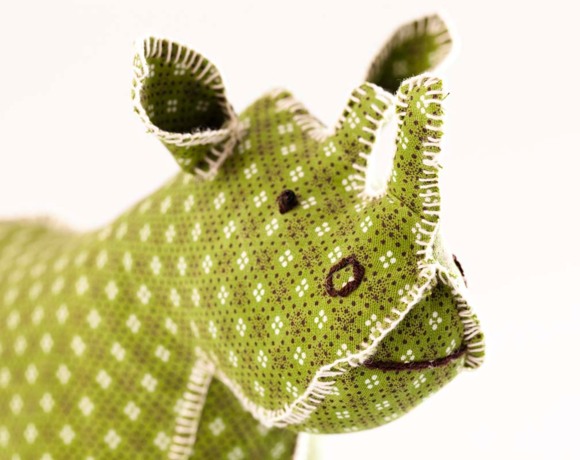 Close-up of a handmade soft fabric rhinoceros toy with green patterned fabric and stitched details