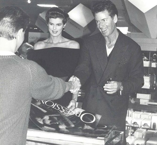 Guests interacting with a smiling man and woman at a hotel retail or gift shop counter under modern ceiling lights