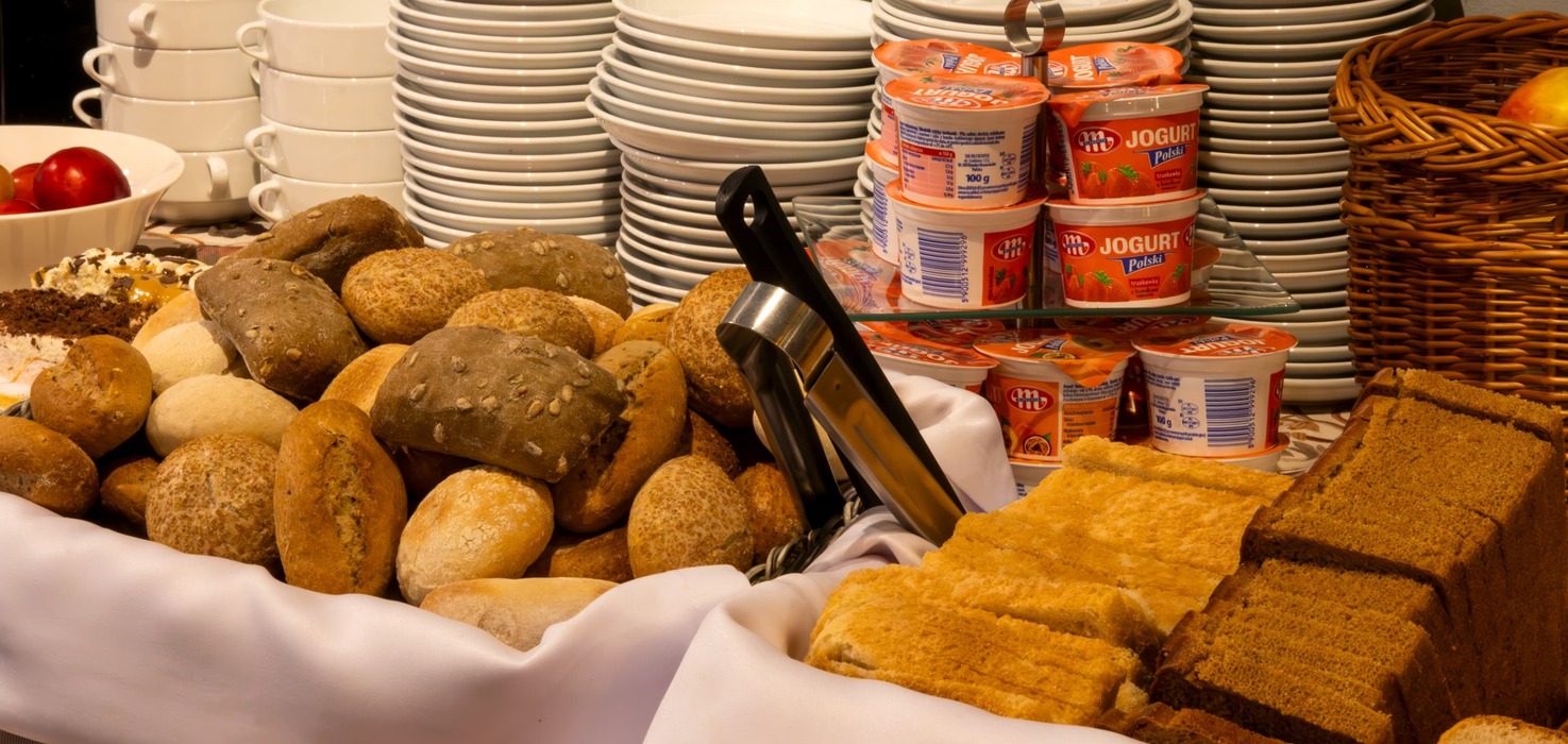 Bufet śniadaniowy z pieczywem, tostami, jogurtami i talerzami
