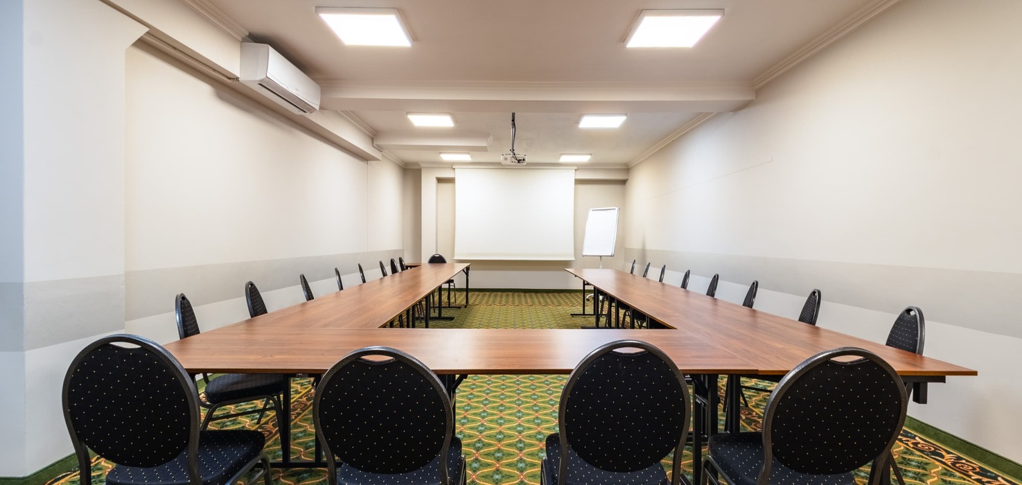 Conference room with tables in a horseshoe layout and a projection screen.