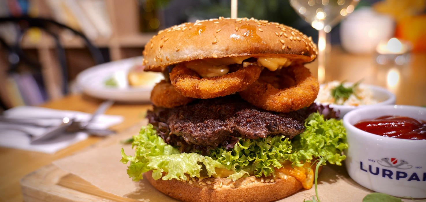 Burger wołowy z sałatą i krążkami cebulowymi w restauracji hotelowej