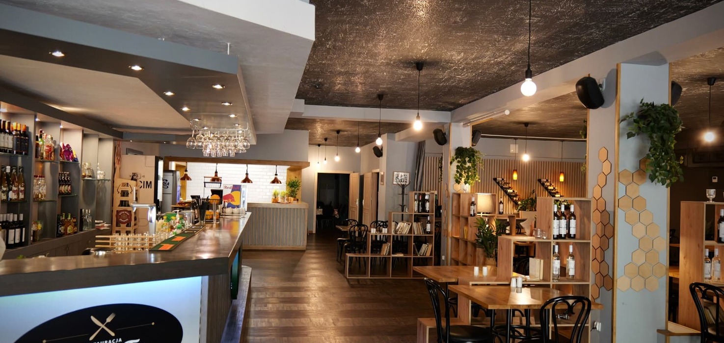 Contemporary hotel restaurant with long bar, wooden tables, wine displays, hanging bulbs and warm cozy lighting