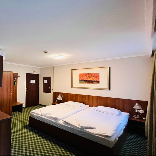 Pokój hotelowy z podwójnym łóżkiem i aneksem kuchennym.