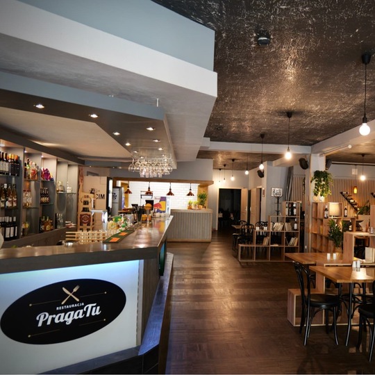 Nowoczesna restauracja hotelowa z długim barem, drewnianymi stolikami, półkami z win, wiszącymi lampami i przytulnym oświetleniem