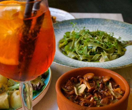 Restaurant dishes with salad, bread, and a colorful drink at the table