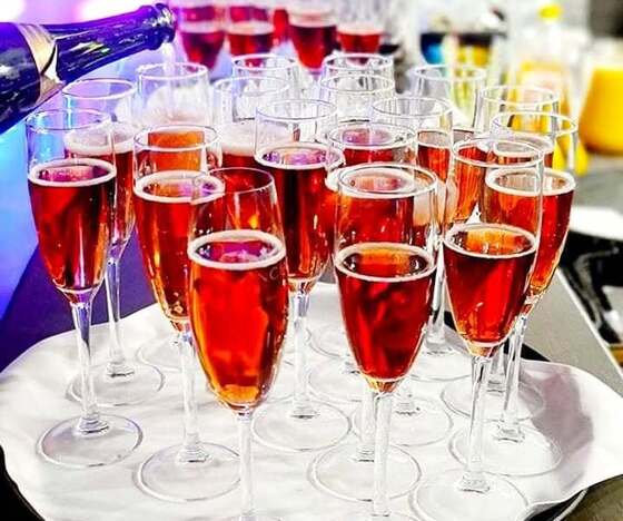 Sparkling rosé flutes arranged on a tray at a hotel bar, a bottle pouring for a celebratory reception.
