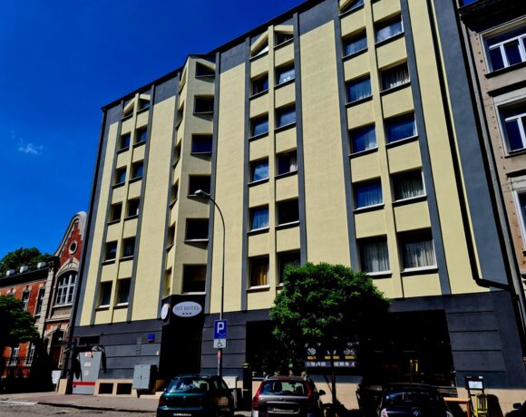 Photo of the facade of Hit Hotel in Warsaw against the sky.