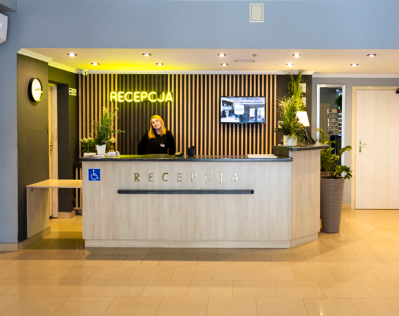 Uśmiechnięta recepcjonistka i nowoczesny, zadbany hol recepcji Hotelu.