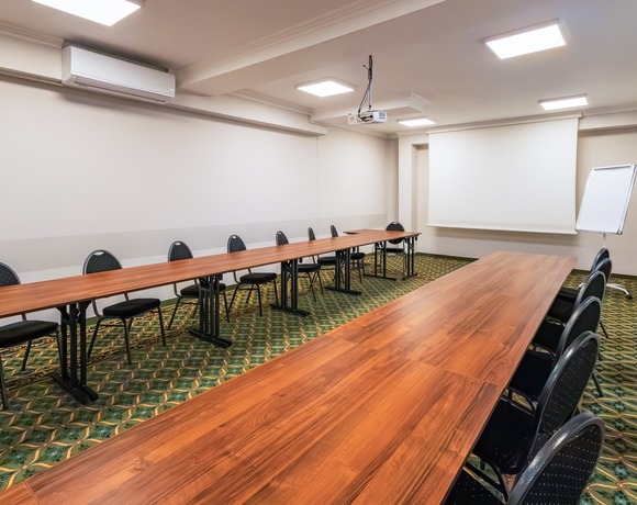 Conference room with tables in a classroom layout, a lowered projection screen, and a projector suspended from the ceiling.