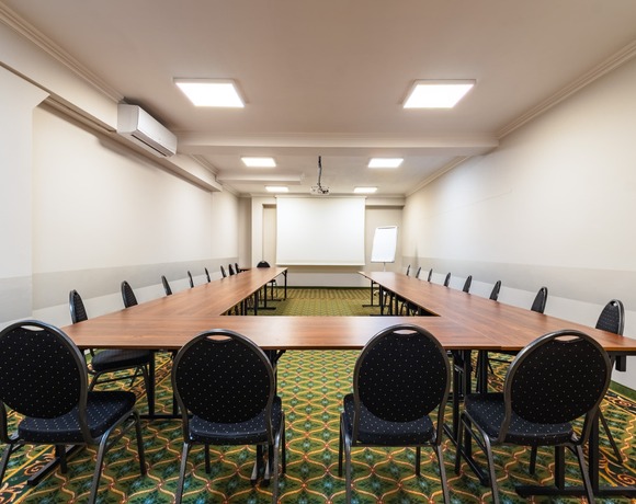 Conference room with tables in a horseshoe layout and a projection screen.