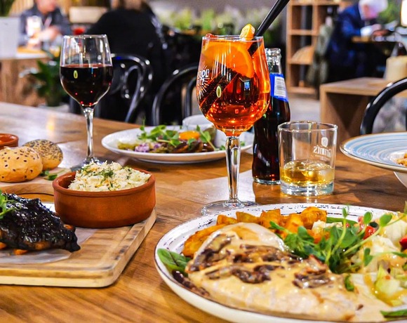 Przytulna restauracja serwująca pyszne, wspólne dania: glazurowane żeberka na frytkach, makaron, sałatkę, pieczywo, surówkę i pomarańczowy koktajl – klimatyczne PragaTu w Warszawie ze świetną ofertą kulinarną blisko stacji metra Dworzec Wileński.