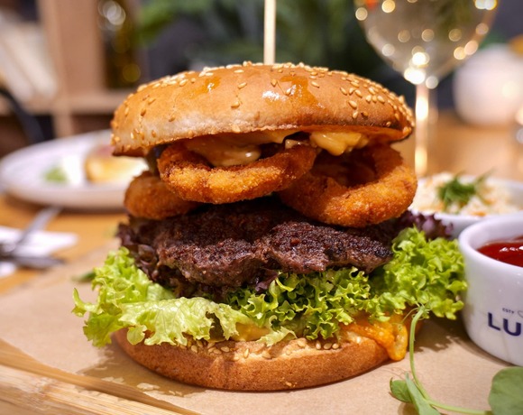 Beef burger with lettuce and onion rings served in the hotel restaurant