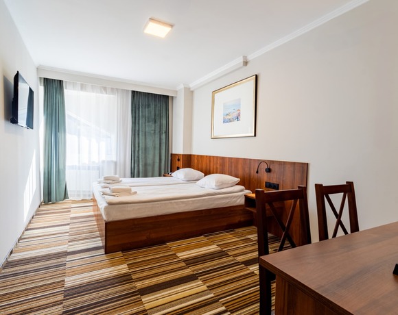 Pokój dwuosobowy DBL z dużym łóżkiem, biurkiem i telewizorem w Hit Hotelu w Warszawie
