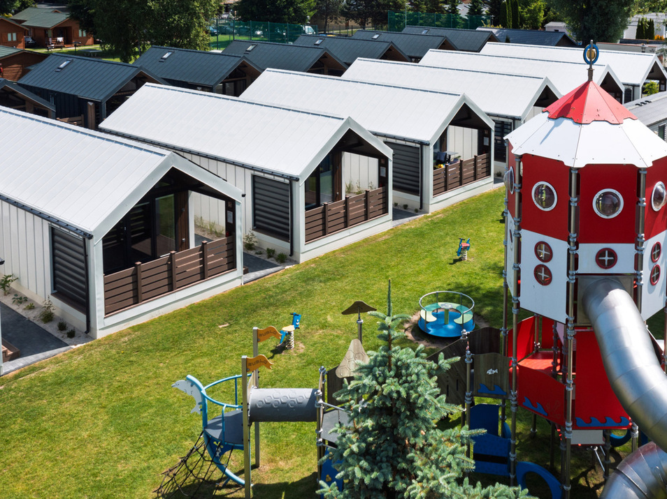 Nowoczesne domki hotelowe z zielonym trawnikiem i dużym placem zabaw z wieżą ze zjeżdżalnią