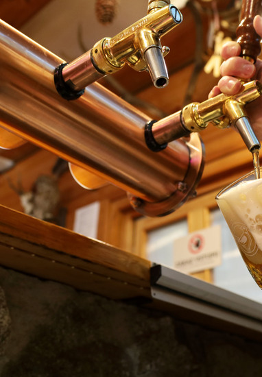 Ruky čapujú pivo s hustou penou z lesklých kohútikov v útulnom rustikálnom hotelovom bare