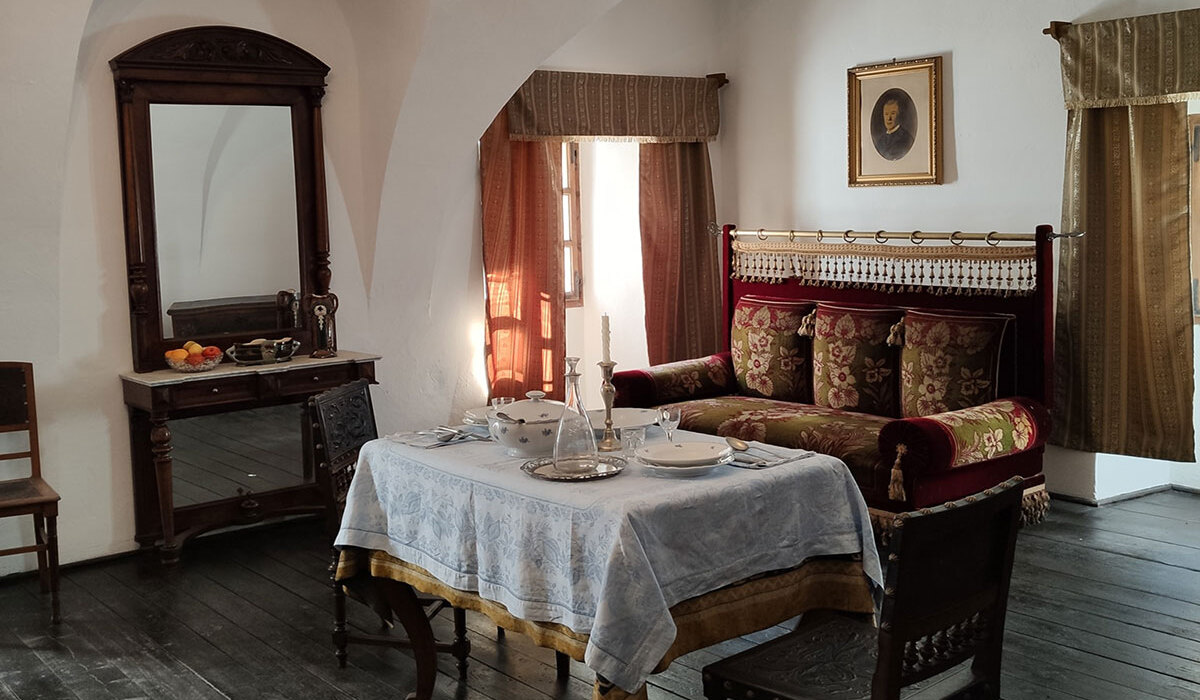 Historic hotel sitting room with arched ceiling, dark wood floors, table set, ornate velvet sofa and antique mirror
