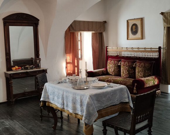 Historic hotel sitting room with arched ceiling, dark wood floors, table set, ornate velvet sofa and antique mirror