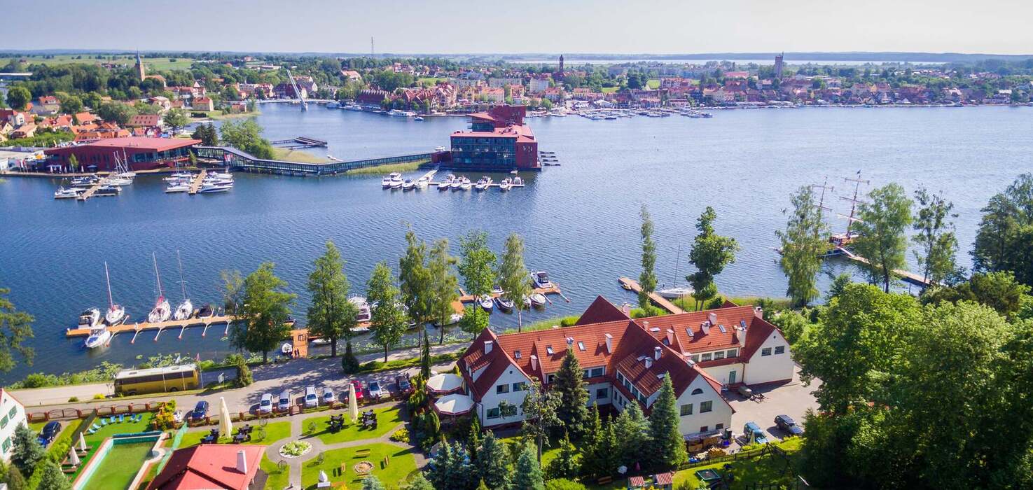 Widok z lotu ptaka na budynek hotelowy z ogrodem i widokiem na jezioro i panoramę miasta