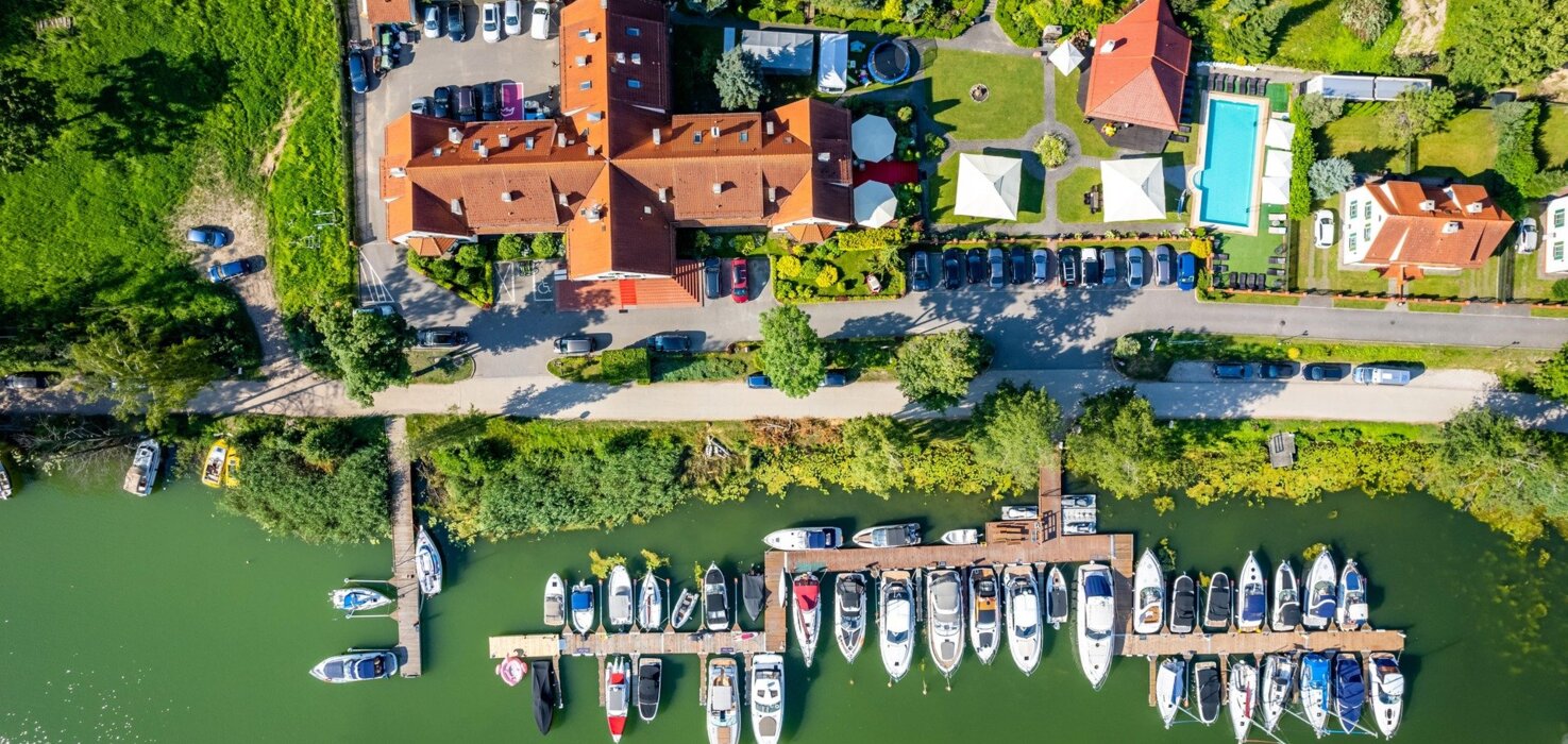 Widok z lotu ptaka na marinę z jachtami i budynki hotelowe z ogrodem i basenem zewnętrznym