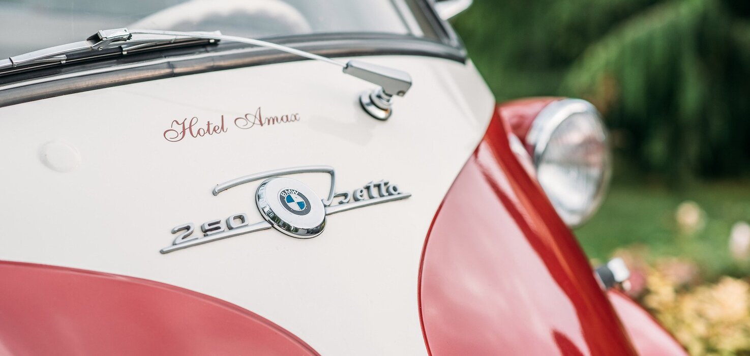 Zbliżenie na przód zabytkowego samochodu BMW z logo hotelu Amax