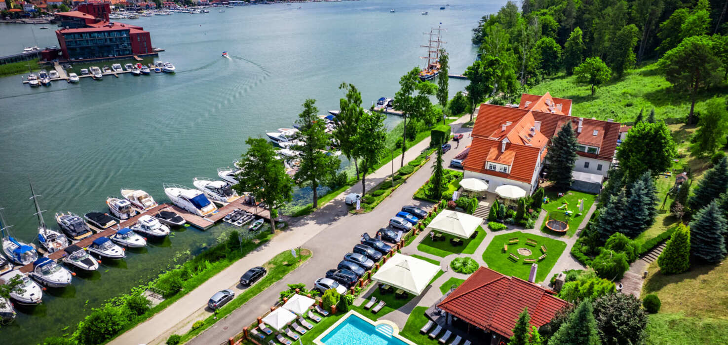 Widok z lotu ptaka na marinę z jachtami i budynki hotelowe z ogrodem i basenem zewnętrznym