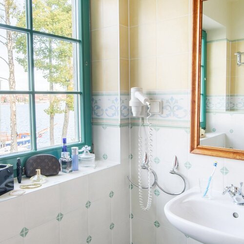 Łazienka w apartamencie willowym z umywalką i oknem z widokiem na jezioro