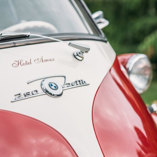 Zbliżenie na przód zabytkowego samochodu BMW z logo hotelu Amax