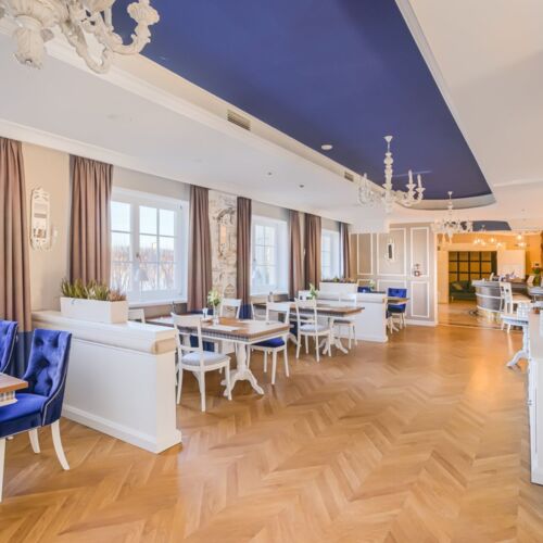 Sala restauracyjna ze stolikami i oknami z widokiem na jezioro Mikołajskie