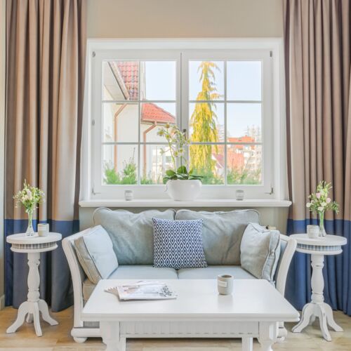 Przytulny kącik wypoczynkowy z kanapą i stolikiem, z dużym oknem