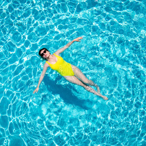 Kobieta pływająca w stroju kąpielowym w basenie zewnętrznym