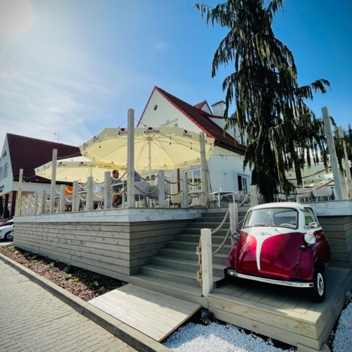 Wejście na taras restauracyjny obok zabytkowego samochodu BWM z logo Hotelu Amax