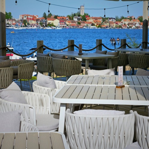 Widok na stolik restauracyjny na tarasie z widokiem na jezioro i promenadę Mikołajek
