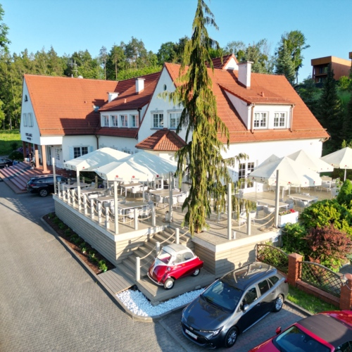 Widok z lotu ptaka na taras restauracyjny ze stolikami, krzesłami i parasolami