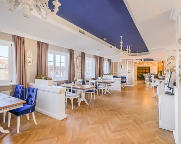 Sala restauracyjna ze stolikami i oknami z widokiem na jezioro Mikołajskie