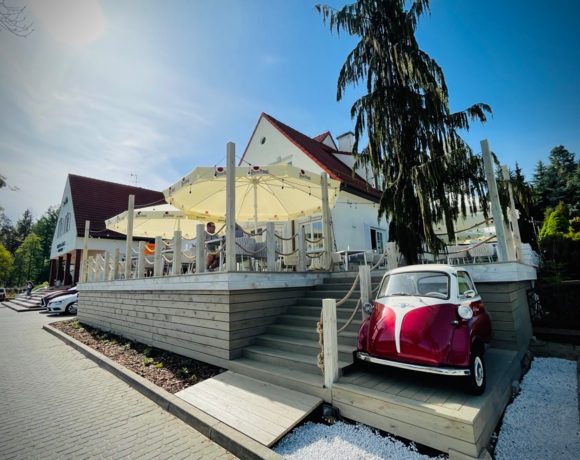 Wejście na taras restauracyjny obok zabytkowego samochodu BWM z logo Hotelu Amax