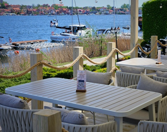 Widok na stolik restauracyjny na tarasie z widokiem na jezioro i promenadę Mikołajek