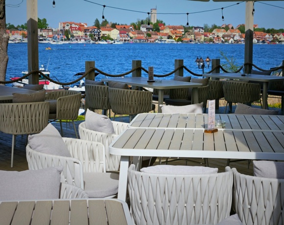 Widok na stolik restauracyjny na tarasie z widokiem na jezioro i promenadę Mikołajek
