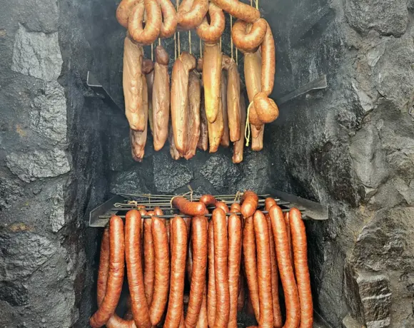 Wędzona kiełbasa wisząca w wędzarni z kamienia