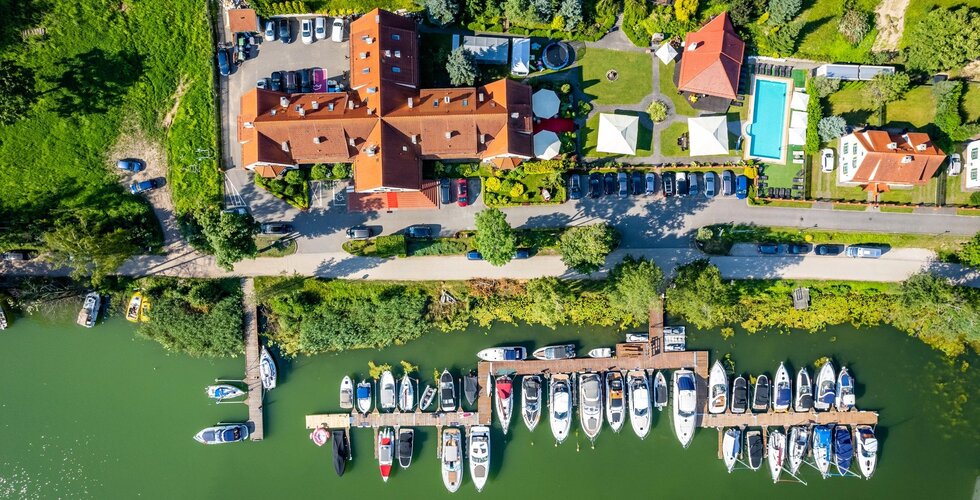 Widok z lotu ptaka na marinę z jachtami i budynki hotelowe z ogrodem i basenem zewnętrznym