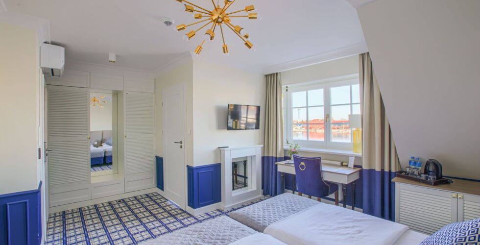 Nowoczesny pokój hotelowy z dwoma łóżkami, biurkiem i dużym oknem