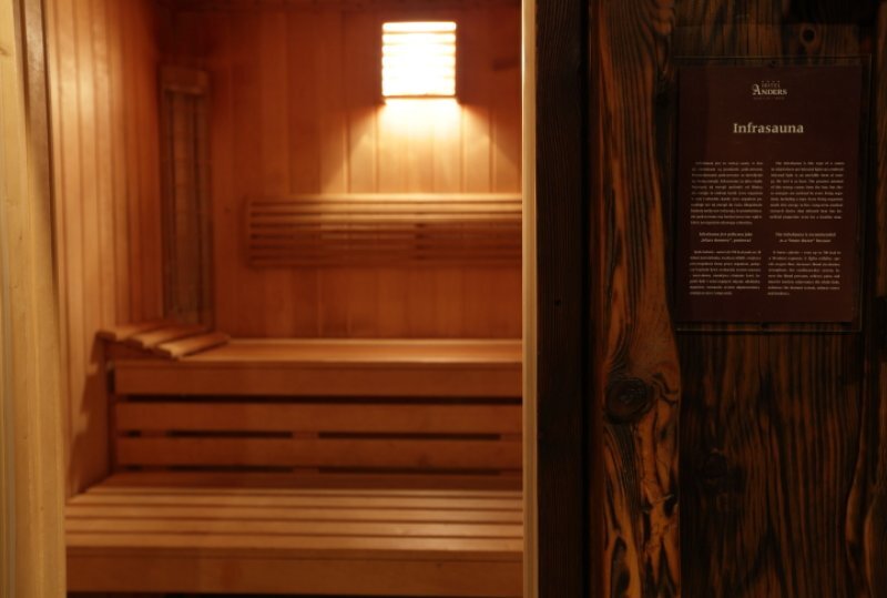 Infrarotsauna mit warmem Licht, gestaffelten Holzbänken und sanfter Wandleuchte, entspannender Spa-Bereich.