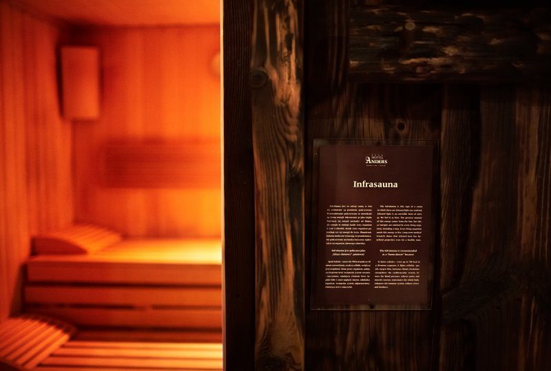 Warm beleuchtete Infrasauna mit Holzliegen und Innenlampe, Bereich des Hotel‑Spas zum Entspannen.