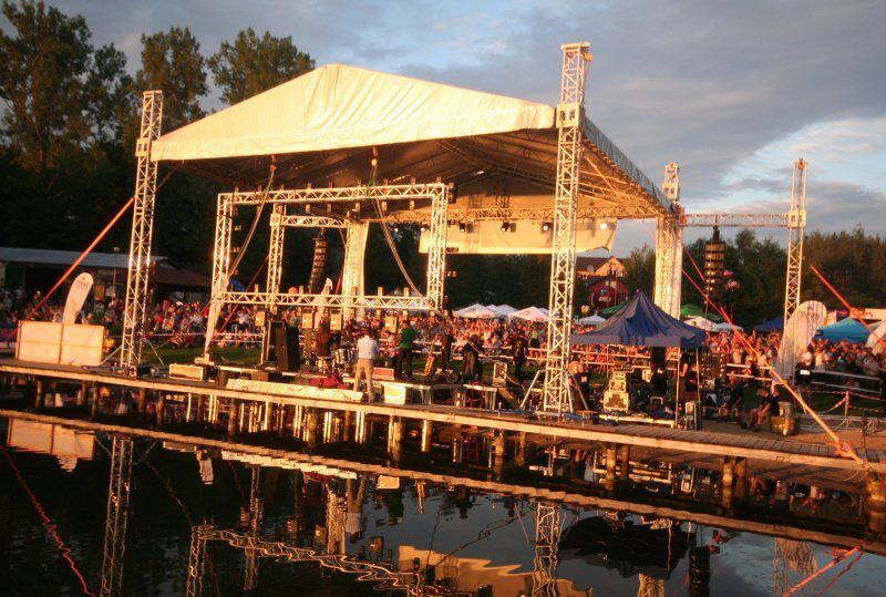 Wasserbühne mit Überdachung, Live-Band und Abendpublikum, Spiegelung in ruhigem Wasser