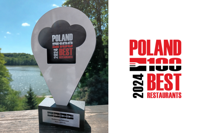 Trophäe in Form einer Kochmütze 'Poland 100 Best Restaurants 2024' für Restauracja Pałacowa Stare Jabłonki auf Holzgeländer am See