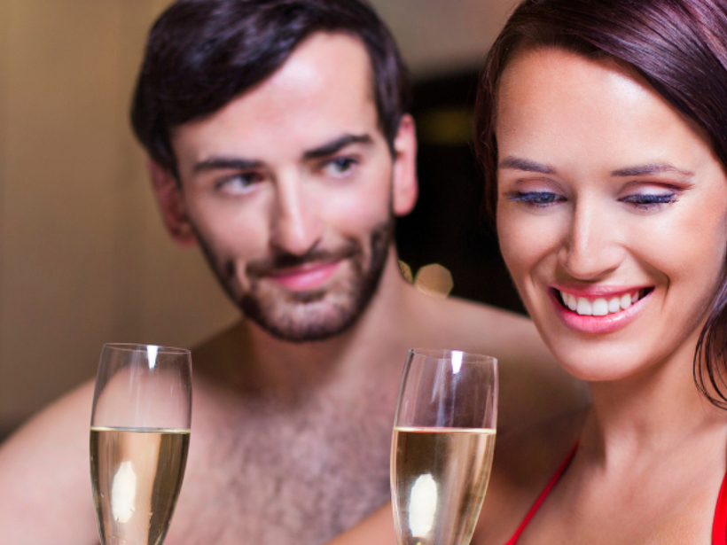 Paar in Badebekleidung trinkt Champagner im Hotel-Whirlpool, warmes Licht und entspannte, romantische Spa-Atmosphäre