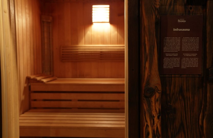 Infrarotsauna mit warmem Licht, gestaffelten Holzbänken und sanfter Wandleuchte, entspannender Spa-Bereich.