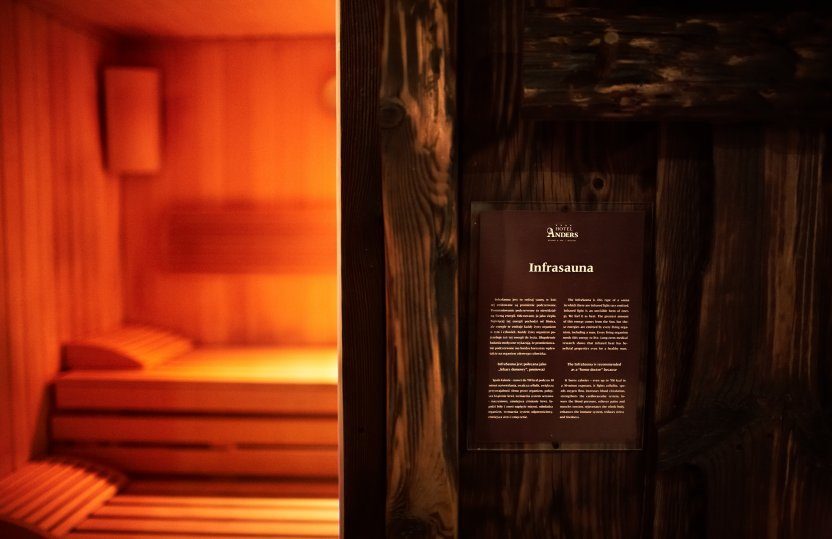 Warm beleuchtete Infrasauna mit Holzliegen und Innenlampe, Bereich des Hotel‑Spas zum Entspannen.