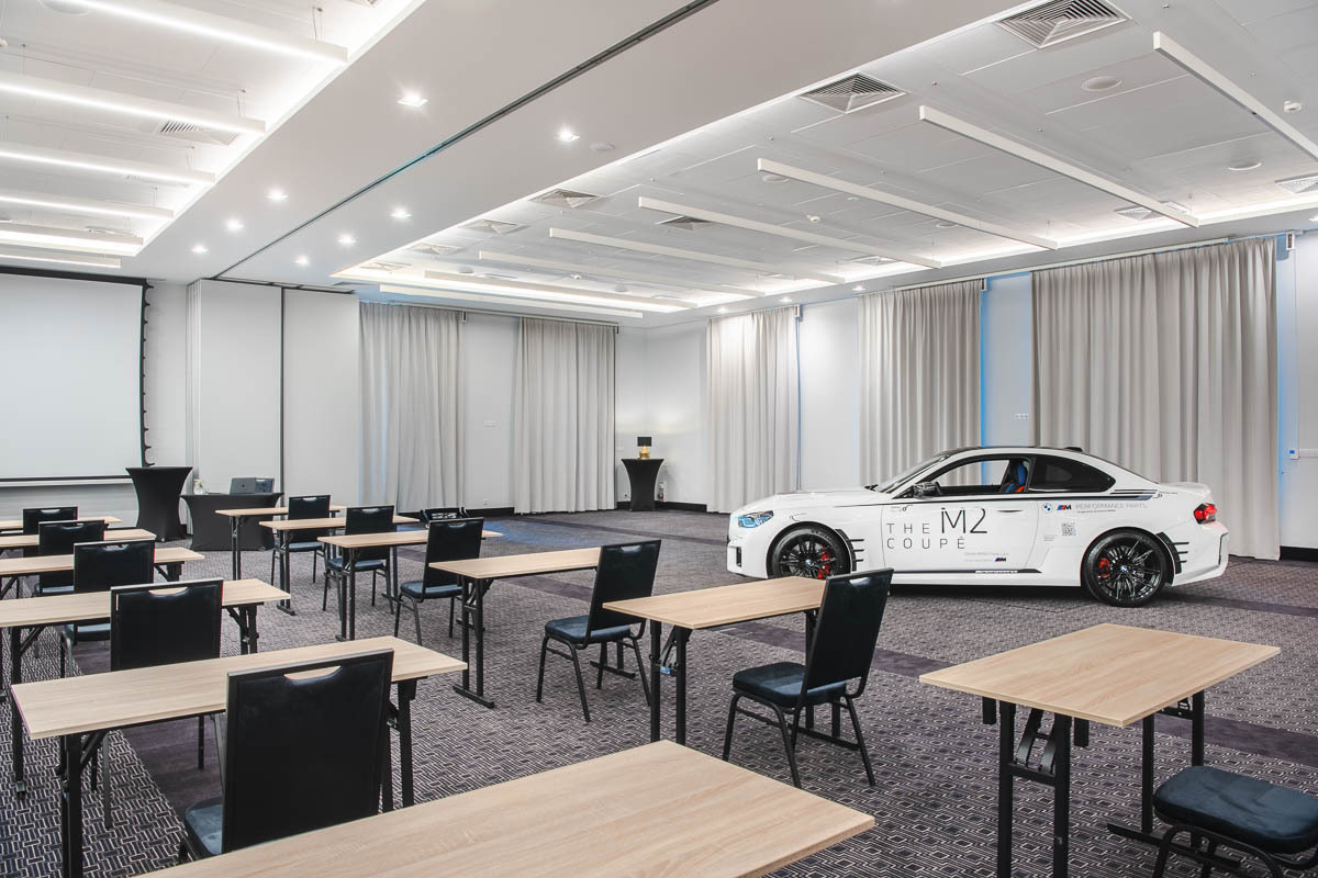 Przestronna, jasna sala konferencyjna z ustawionymi w układzie szkolnym stołami